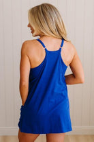 Blonde woman wearing a solid blue romper dress with side pockets.