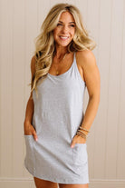 Woman wearing a gray sleeveless dress against a beige wall