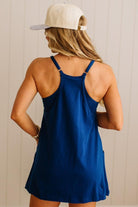 Woman wearing a blue tank top and beige cap against a neutral background