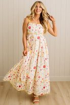 Woman wearing a floral dress against a wooden paneled wall.