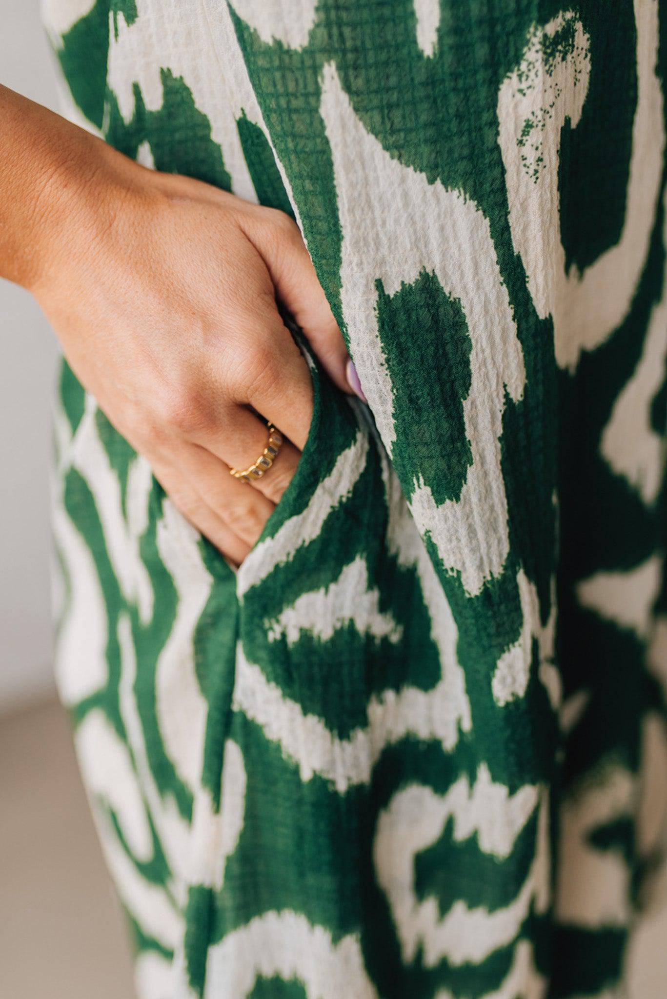 BLONDE WOMAN WEARING A GREEN AND CREAM ABSTRACT PRINTED FRILL SLEEVE SHIRT MINI DRESS.