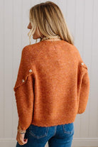 BLONDE WOMAN WEARING DARK JEANS IN A BRIGHTLY LIT STUDIO WITH A SOLID SWEATER FEATURING SCALLOP TRIM AND BUTTONS UP THE SLEEVE IN THE COLOR HEATHERED RUST.