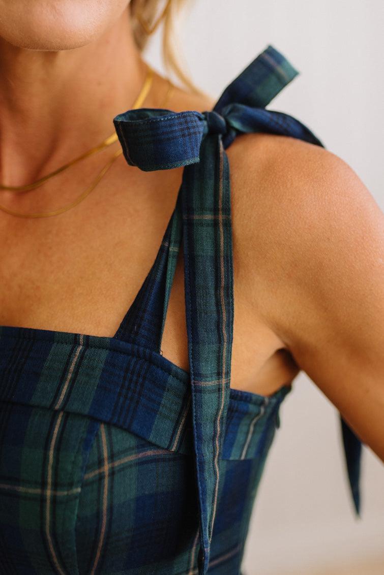 Close-up of a model wearing a blue and green plaid halter top with a tie-shoulder design.