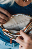 Close-up of a person holding a beige handbag with two interior mesh pockets.