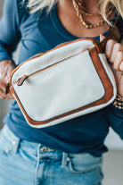 Person holding a white handbag with brown accents