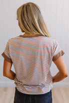 Woman wearing a striped shirt with brown and white colors against a plain background