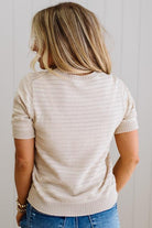 Person wearing a beige knit sweater and blue jeans against a white background