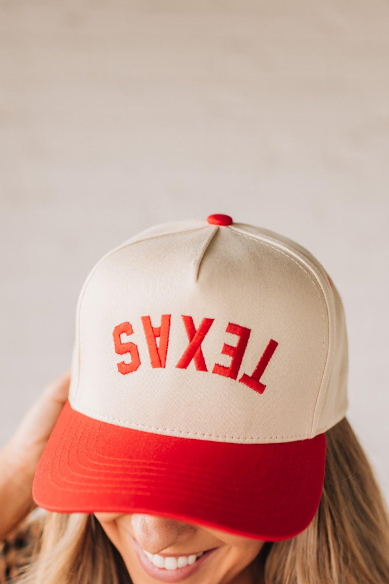 Blonde woman in leopard dress wearing a cream hat with red brim and red TEXAS embroidered upside down at the front.