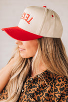 Blonde woman in leopard dress wearing a cream hat with red brim and red TEXAS embroidered upside down at the front.