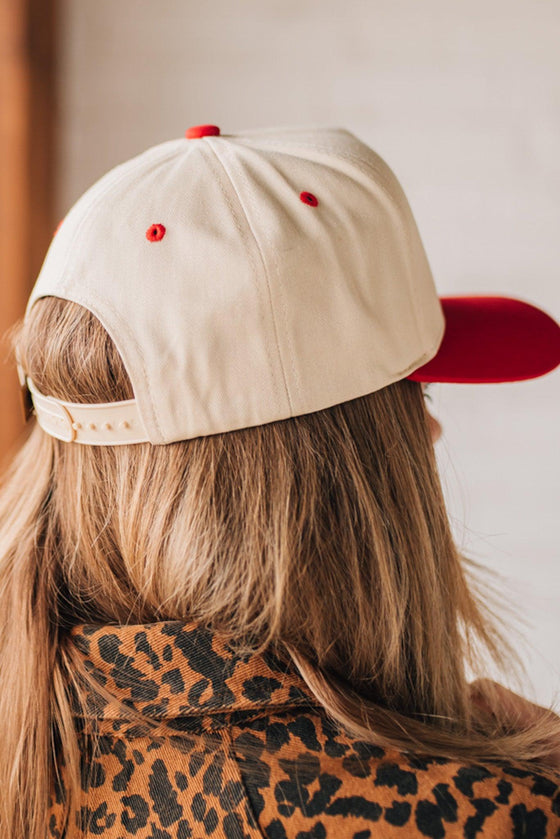 Blonde woman in leopard dress wearing a cream hat with red brim and red TEXAS embroidered upside down at the front.