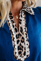 Close-up of a person wearing a blue top with a leopard print scarf