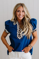 Woman wearing a blue top with leopard print details against a light background