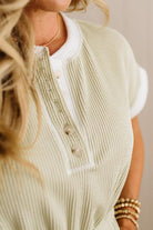 Close-up of a person wearing a light green knitted cardigan with white trim.