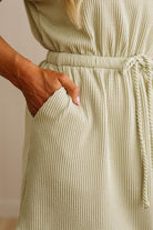Close-up of a person wearing a ribbed knit dress with a neutral background