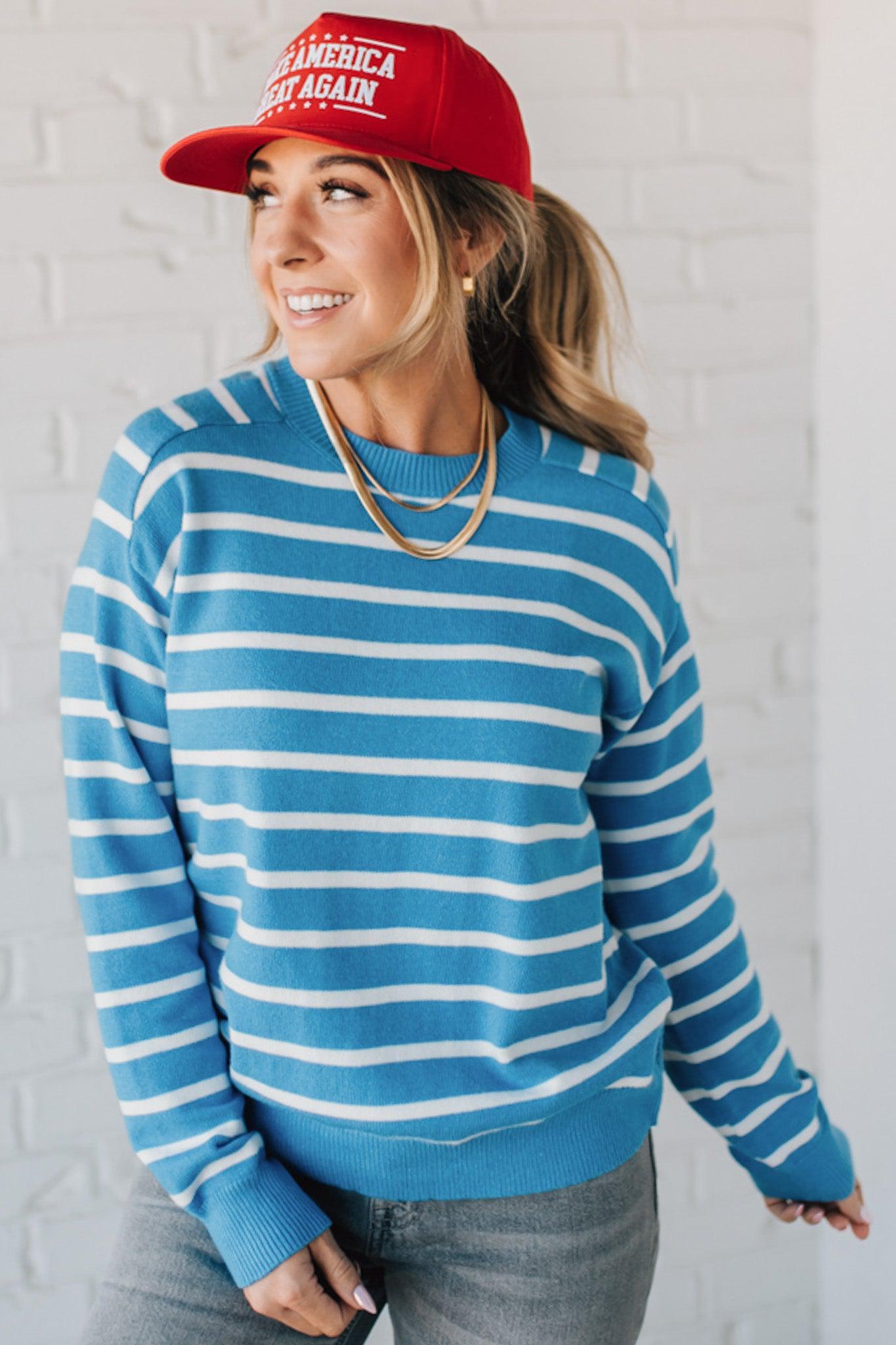 Blue and white striped crew neck sweater on blonde woman wearing a red hat.