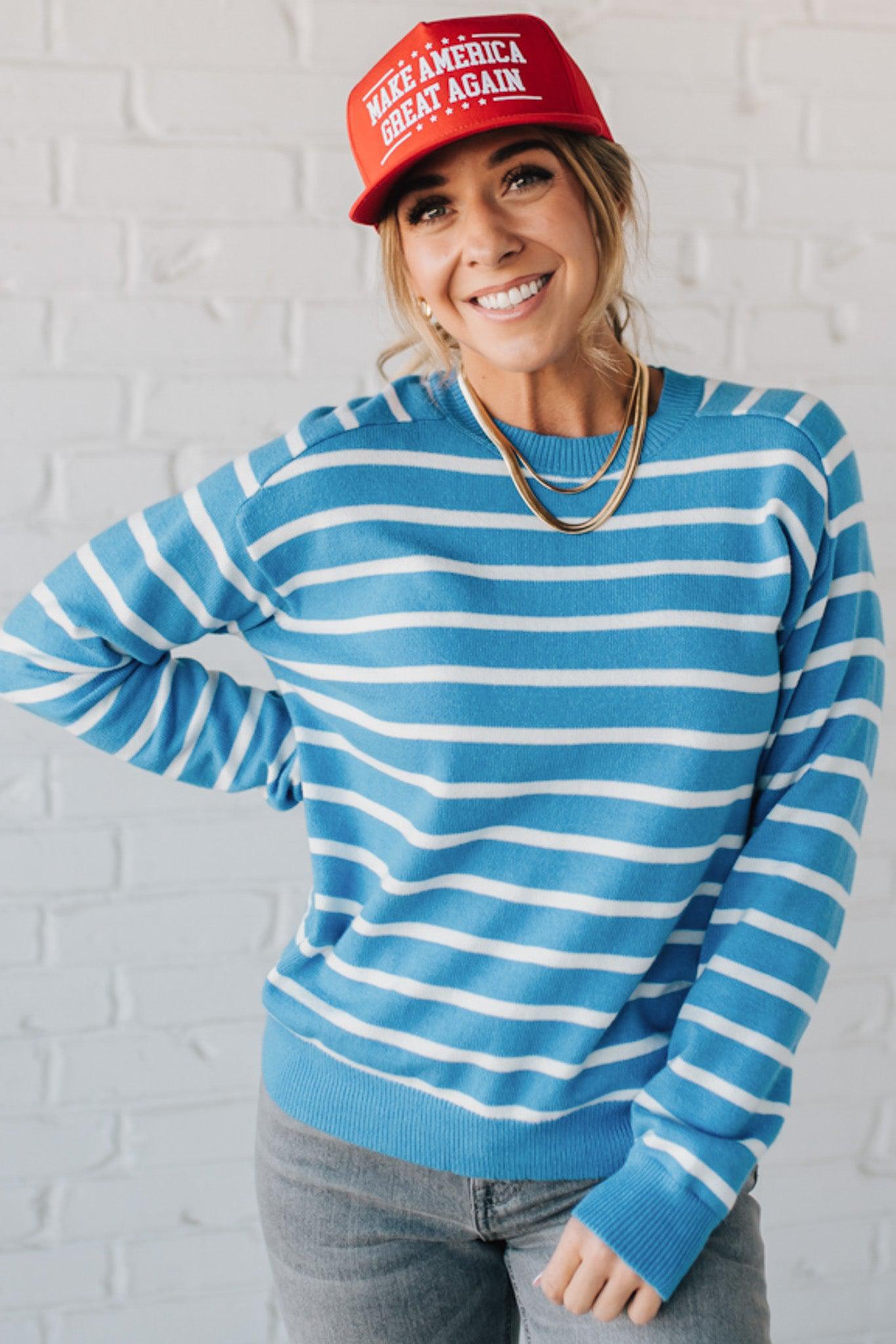 Blue and white striped crew neck sweater on blonde woman wearing a red hat.