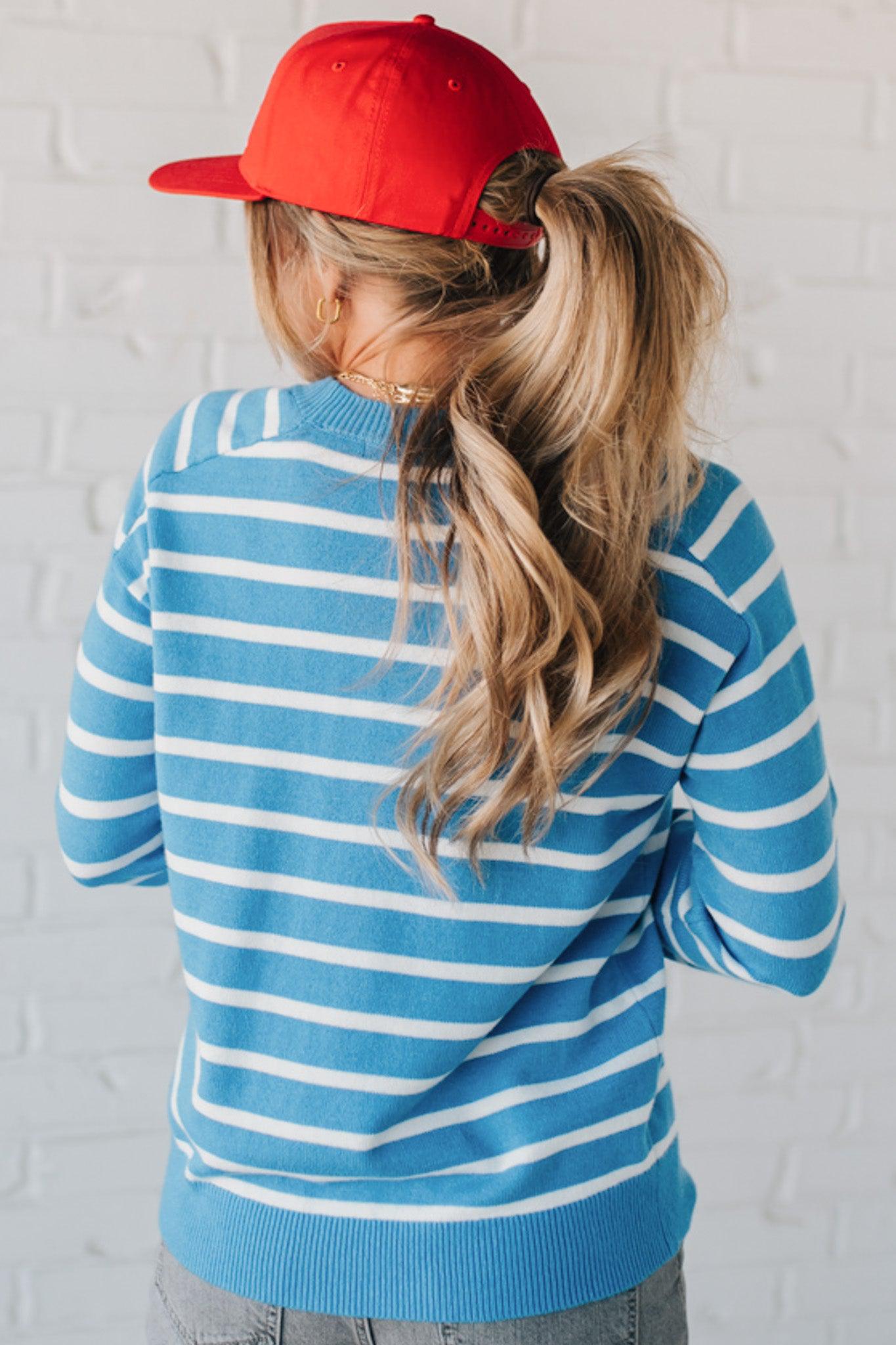 Blue and white striped crew neck sweater on blonde woman wearing a red hat.