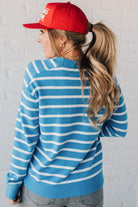 Blue and white striped crew neck sweater on blonde woman wearing a red hat.