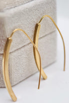 Gold hoop earrings on a textured fabric background