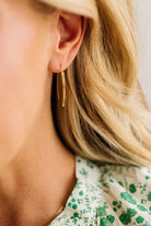Close-up of a person wearing a gold hoop earring with a blurred background