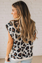 Blonde woman wearing a cream short sleeve sweater with all over bold brown and black leopard pattern, and double white ties on each side.