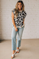 Blonde woman wearing a cream short sleeve sweater with all over bold brown and black leopard pattern, and double white ties on each side.