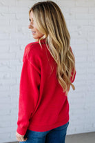 Woman wearing a red sweater with a white brick wall background