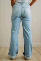 Light blue jeans worn by a person against a white paneled wall.