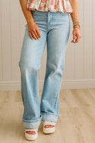 Person wearing light blue jeans and a floral top against a neutral background