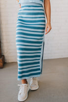 Blonde woman wearing a light blue and medium blue striped sweater ribbed maxi skirt with ribbed stretch waistband, and high side slit.