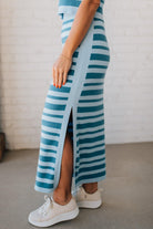 Blonde woman wearing a light blue and medium blue striped sweater ribbed maxi skirt with ribbed stretch waistband, and high side slit.