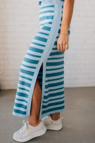 Blonde woman wearing a light blue and medium blue striped sweater ribbed maxi skirt with ribbed stretch waistband, and high side slit.