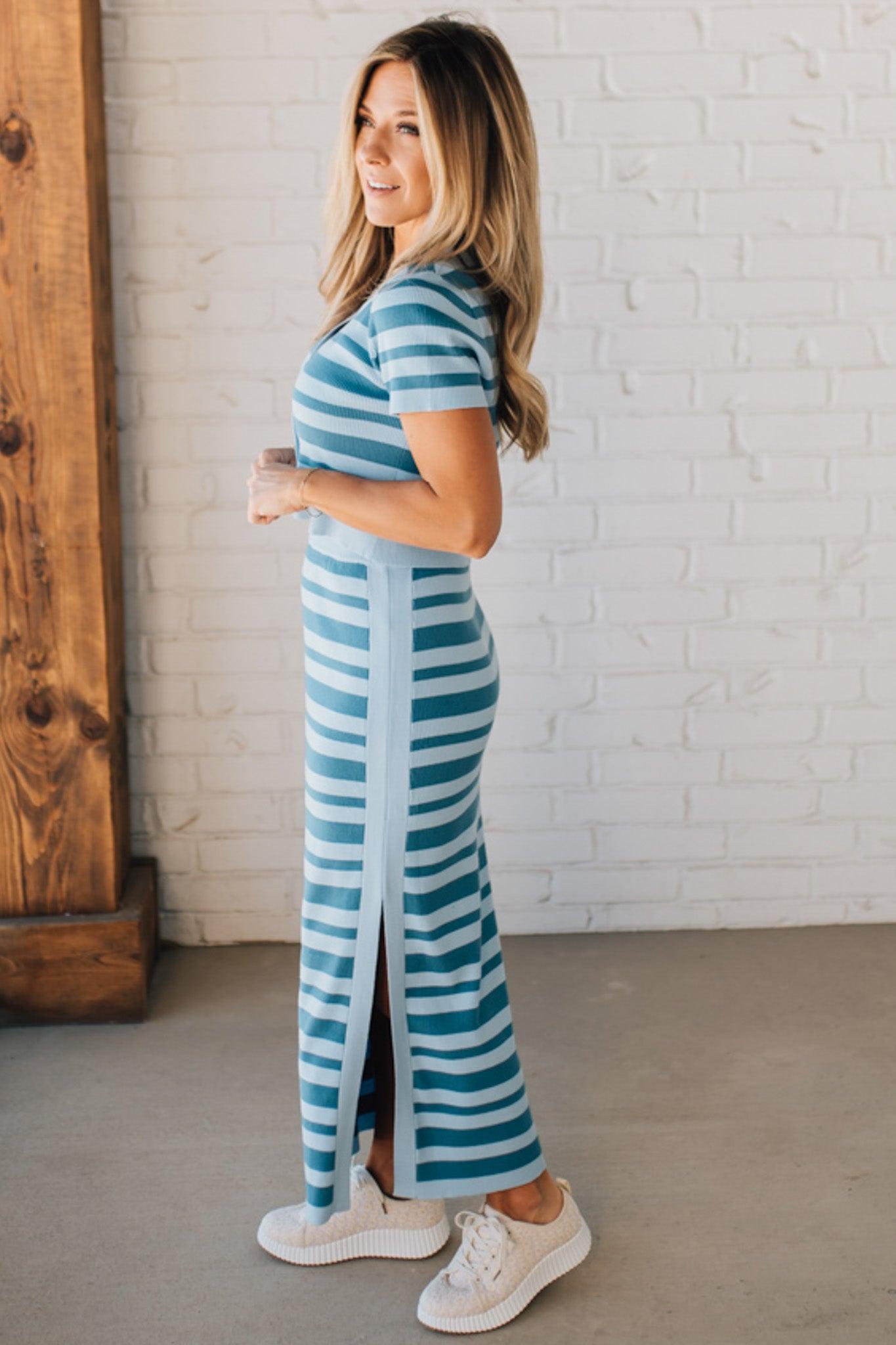 Blonde woman wearing a light blue and medium blue striped sweater ribbed maxi skirt with ribbed stretch waistband, and high side slit.