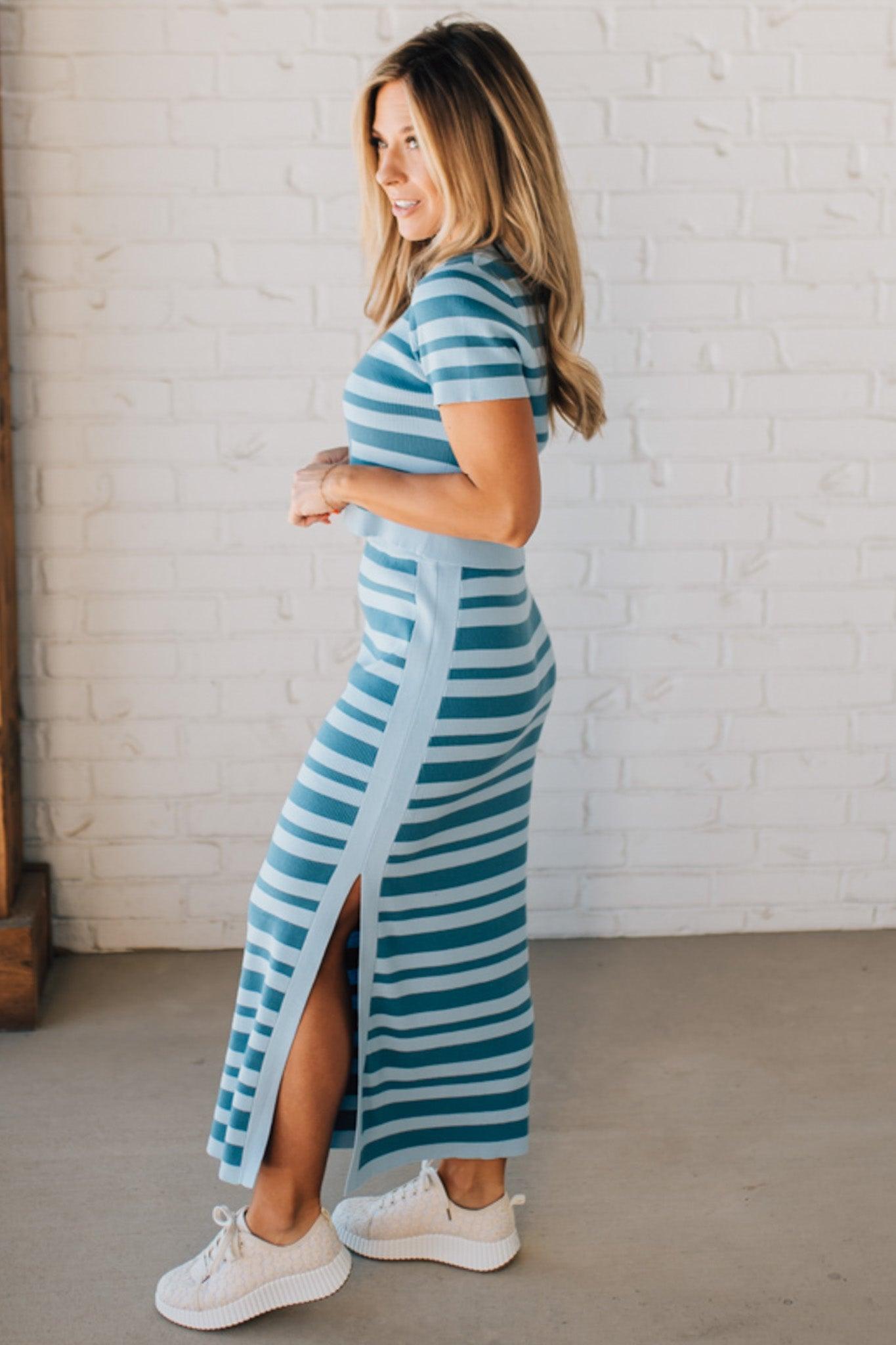 Blonde woman wearing a light blue and medium blue striped sweater ribbed maxi skirt with ribbed stretch waistband, and high side slit.