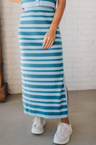 Blonde woman wearing a light blue and medium blue striped sweater ribbed maxi skirt with ribbed stretch waistband, and high side slit.