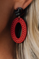 Close-up of a red woven earring with a black center on a blurred background