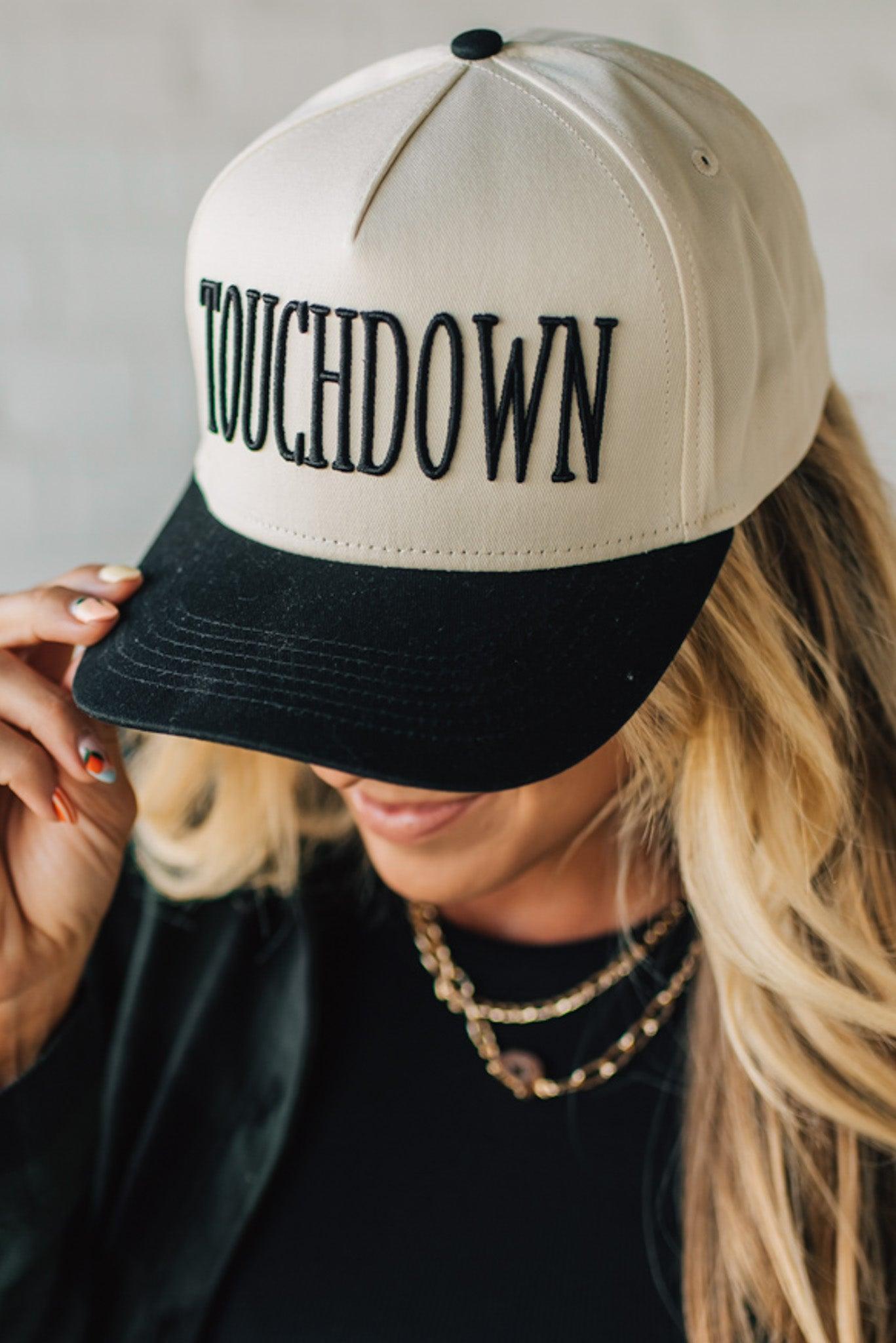 Person wearing a beige and black cap with 'TOUCHDOWN' text on a neutral background