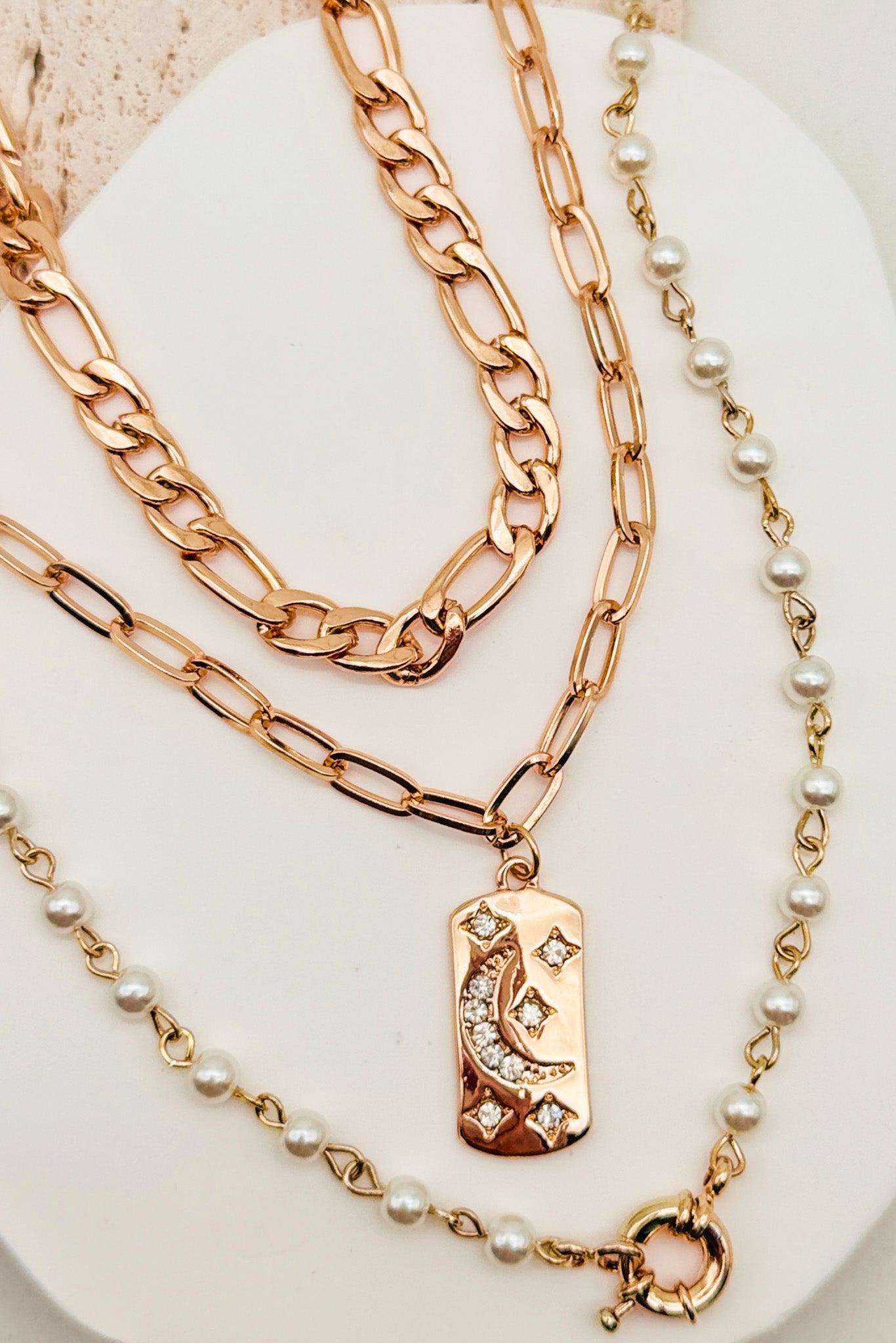 Three gold necklaces with different designs on a white surface