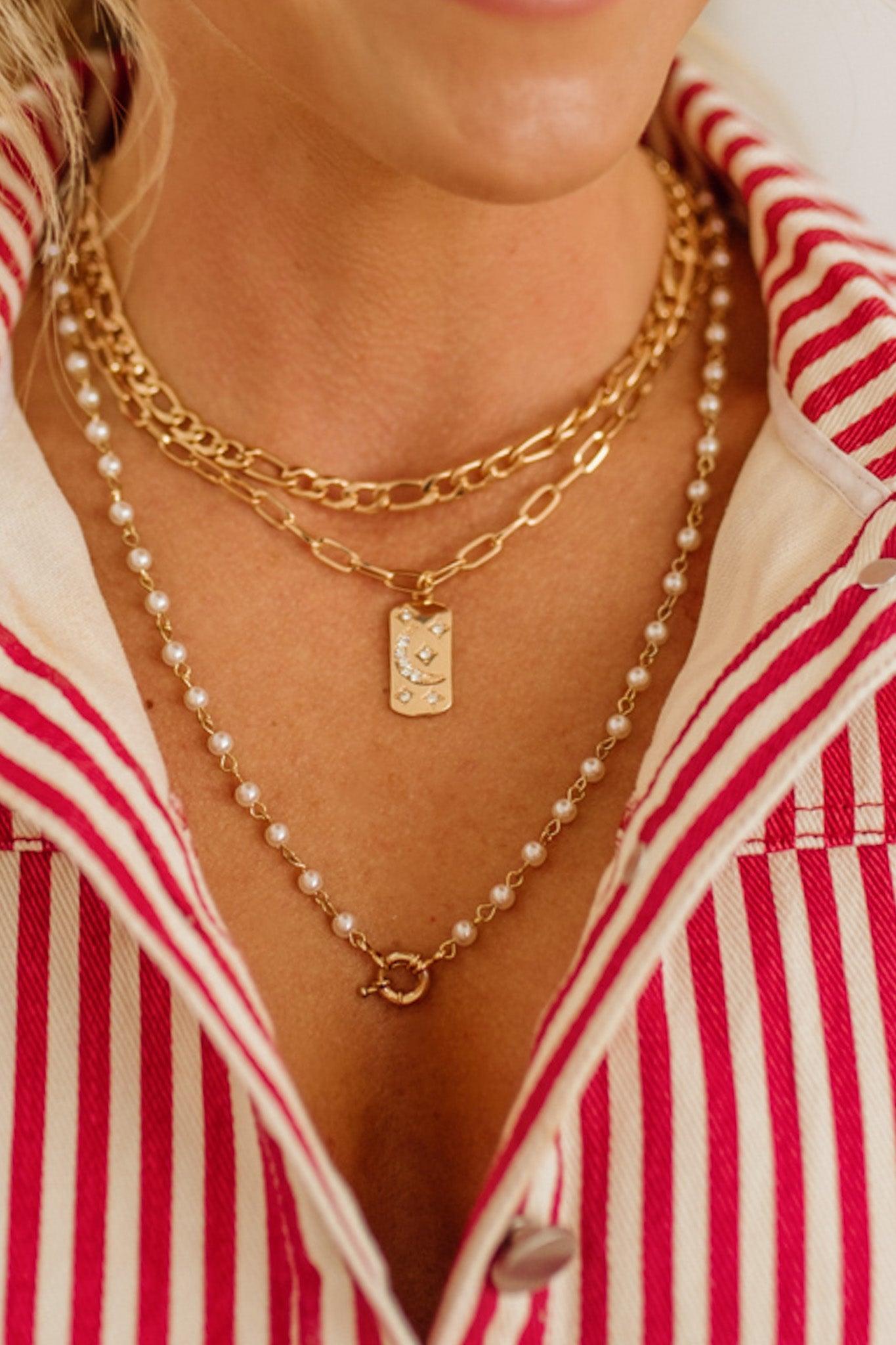 Close-up of layered gold necklaces with a red and white striped shirt