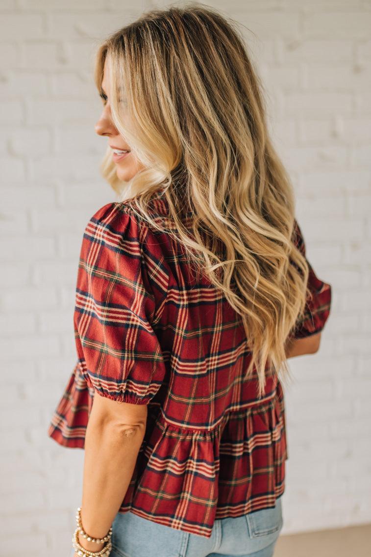 Woman wearing a red plaid shirt with a neutral background