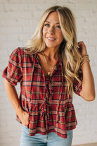 Woman wearing a red plaid shirt with a white brick wall background