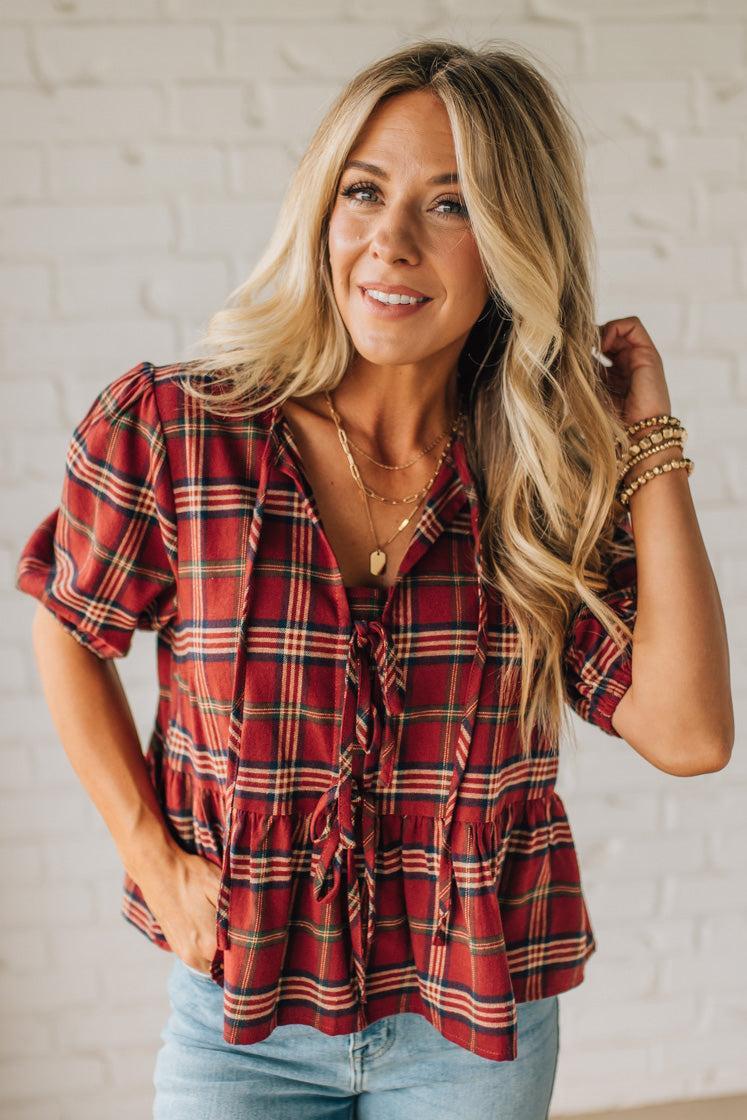 Woman wearing a red plaid shirt with a white brick wall background