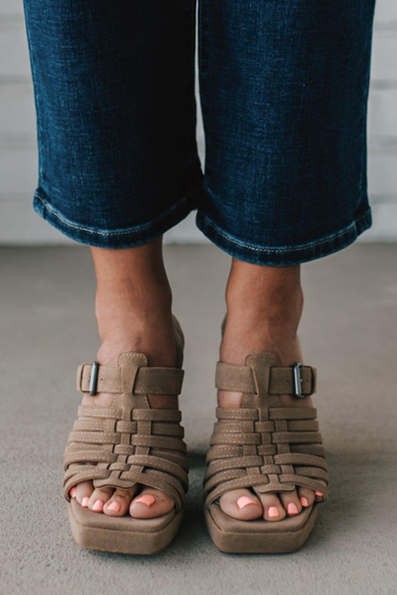 girl modeling an open toe basketweave heel in a neutral taupe color with silver buckle