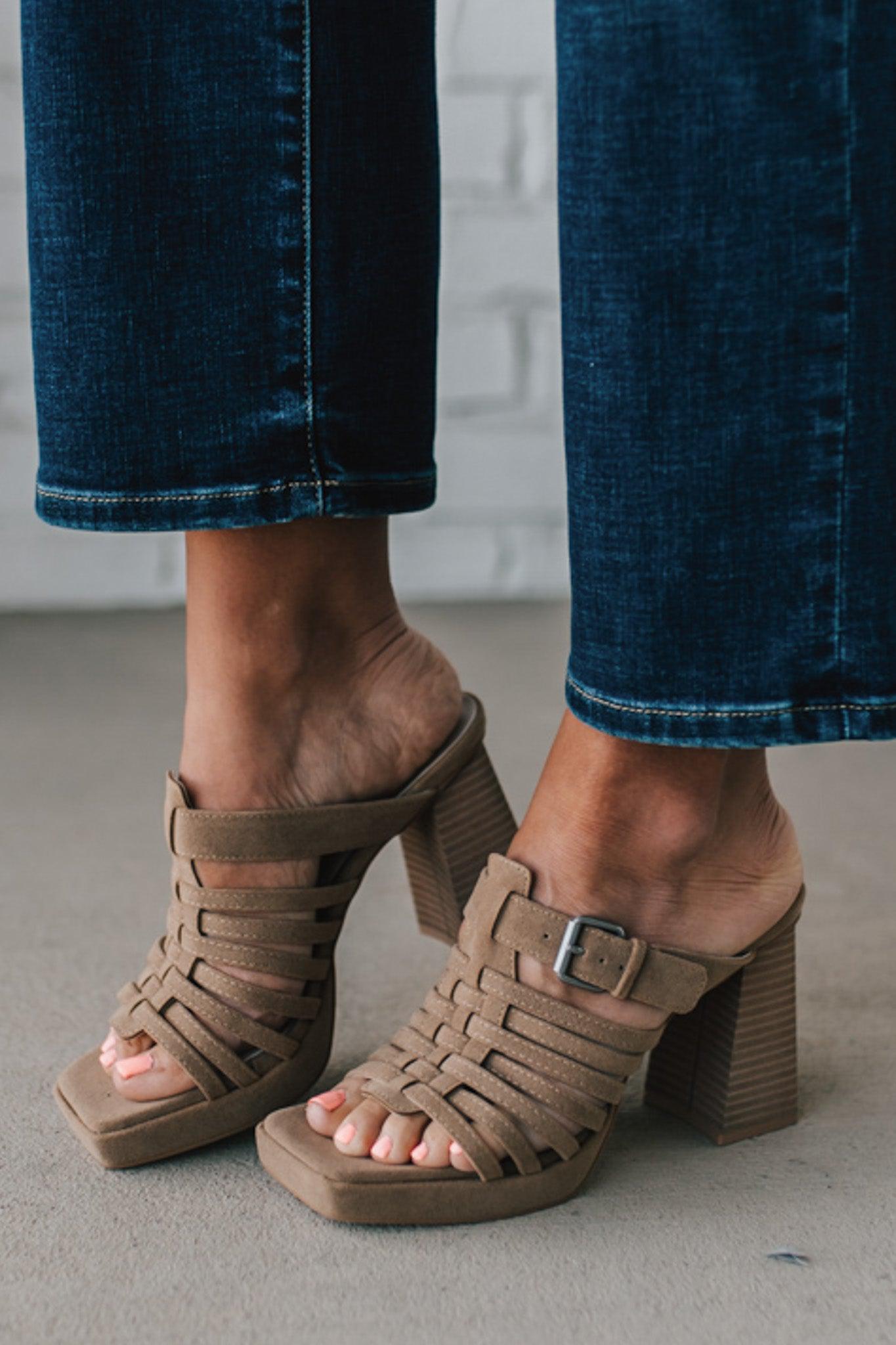 girl modeling an open toe basketweave heel in a neutral taupe color with silver buckle