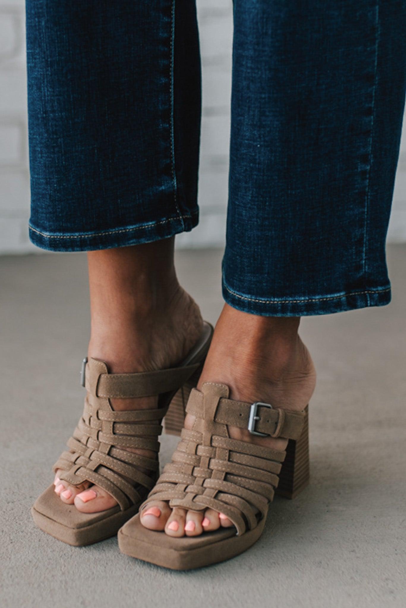 girl modeling an open toe basketweave heel in a neutral taupe color with silver buckle