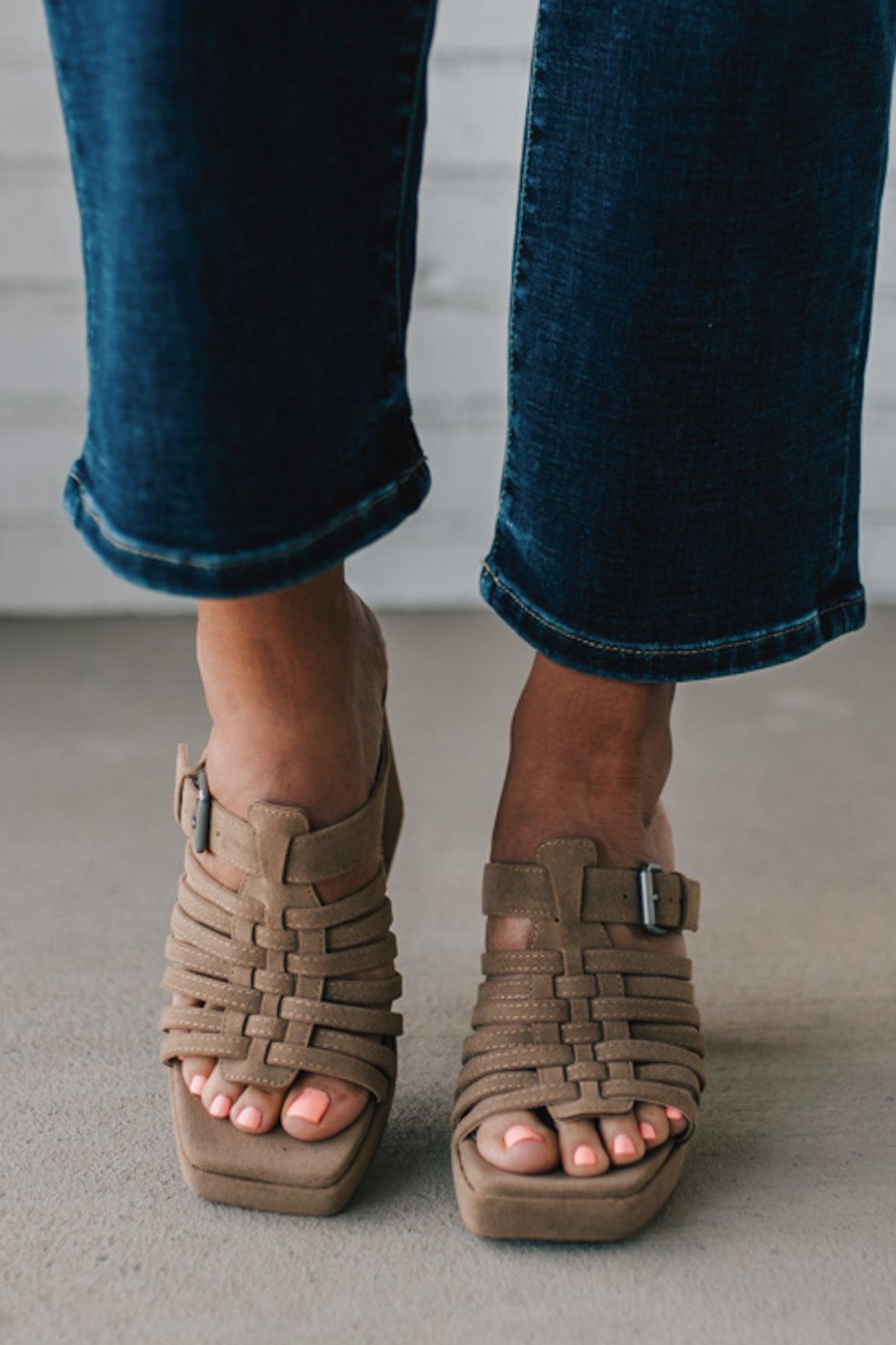 girl modeling an open toe basketweave heel in a neutral taupe color with silver buckle