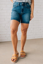 WOMAN WEARING DARK WASH MID-THIGH DENIM SHORT PANTS AND SANDALS.