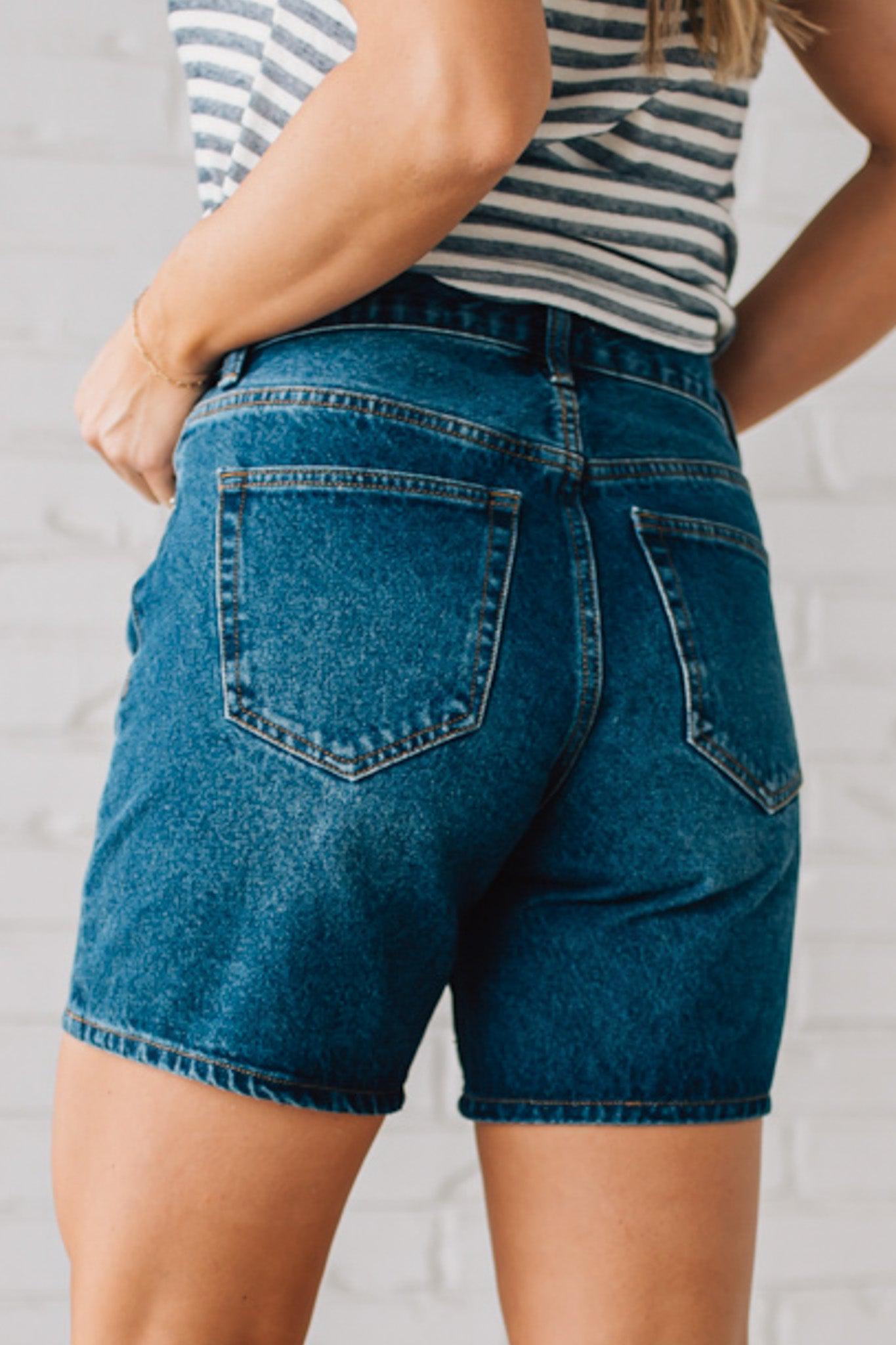 WOMAN WEARING DARK WASH MID-THIGH DENIM SHORT PANTS AND SANDALS.