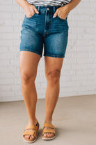 WOMAN WEARING DARK WASH MID-THIGH DENIM SHORT PANTS AND SANDALS.