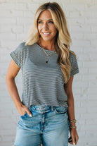 Blonde woman wearing a charcoal grey and white horizontal striped tee with a twist back keyhole accent across the back shoulders.
